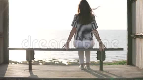一个女人坐在海边的长凳上视频的预览图