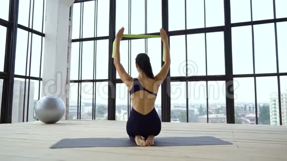 强壮的女孩用橡皮筋做背操视频的预览图