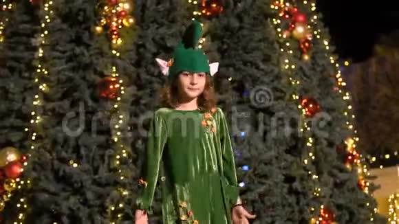小女孩穿着精灵服装跳舞在圣诞树附近唱歌圣诞老人的助手庆祝在圣诞中欢乐视频的预览图