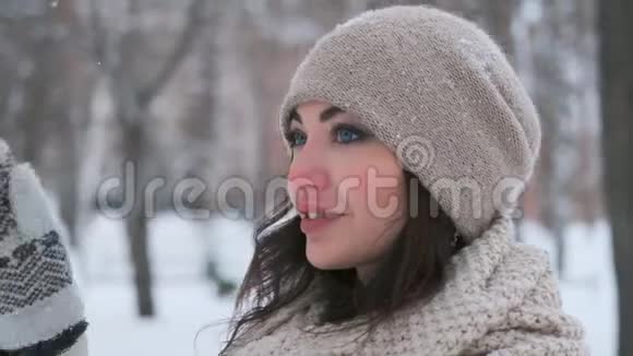 一个戴着深色头发的帽子的漂亮女孩的画像站在公园的冬天笑起来很可爱视频的预览图