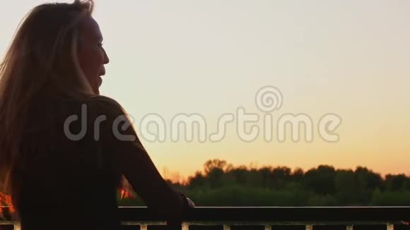 夕阳西下金发姑娘在河边摇着长发视频的预览图