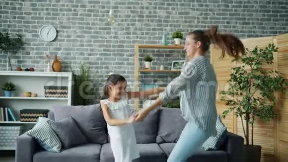 快乐的女孩和年轻有趣的母亲在家跳舞一起跳跃放松视频的预览图