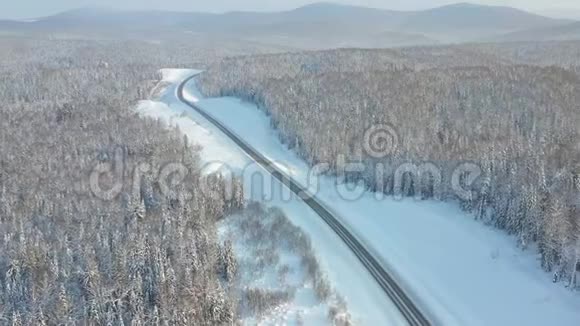 公路穿越冬林航拍无人机白雪覆盖的森林视频的预览图
