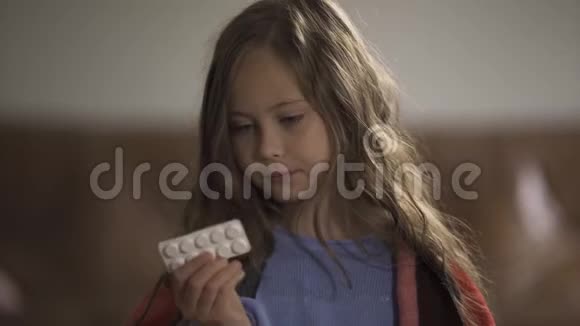 一个病态的白种人女孩在吃药和柠檬之间做出选择坐在家里看着摄像机视频的预览图