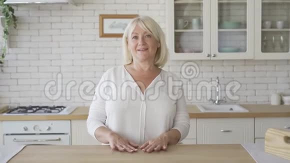 积极成熟的女人看着相机微笑站在现代厨房一位高级女性视频的预览图