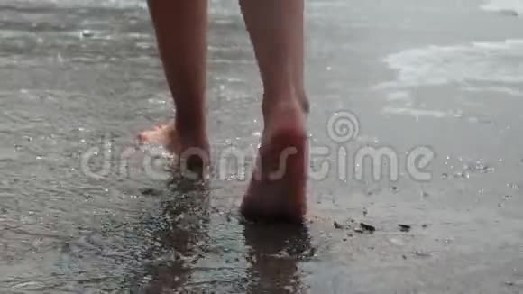 沿着沙质海岸的泡沫海浪向前走的美丽的女性脚的特写镜头奴隶和视频的预览图