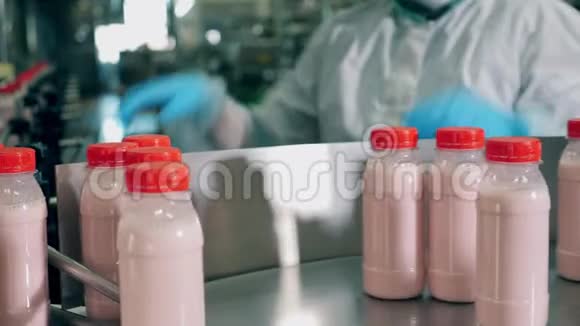 工人正在运送未贴标签的带有酸奶的瓶子视频的预览图