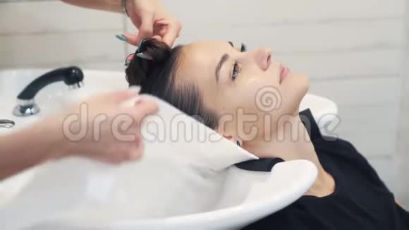 理发师用白色毛巾包裹洗后女性头发动作缓慢视频的预览图