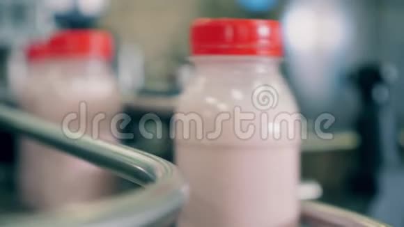 沿传送带移动的无标签酸奶瓶的特写镜头视频的预览图