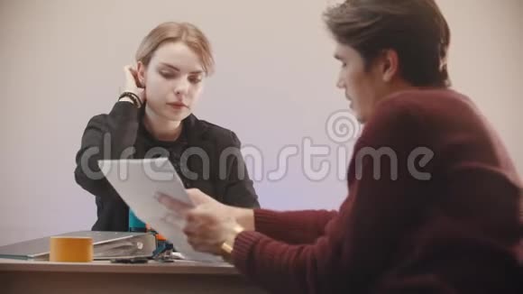办公室一个男人在告诉文件上写着什么女孩在听视频的预览图