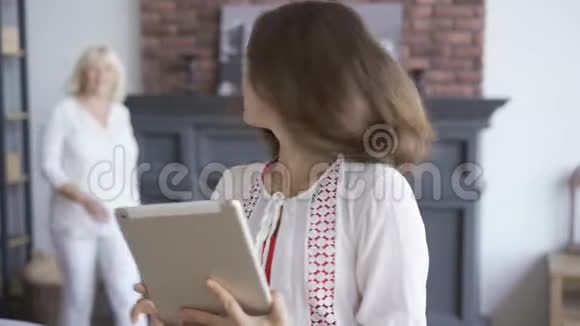 年轻女子的肖像在平板电脑上展示她母亲有趣的东西一家人在一起友好视频的预览图