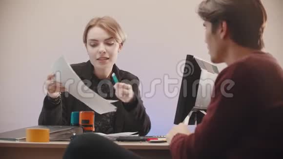 办公室一个女人拿着文件告诉他们上面写着什么男人在听视频的预览图