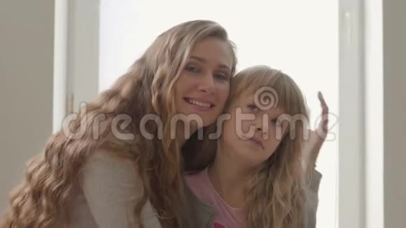快乐的金发白种人母亲在家拥抱她愤怒的小女儿母亲儿童单亲的概念视频的预览图
