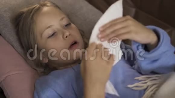 在家里躺在毯子下时一脸病态的白种人女孩打喷嚏这个悲伤的孩子发烧了概念视频的预览图