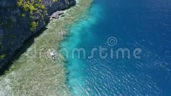 空中4k无人机镜头的banca旅游船停泊在珊瑚礁边缘菲律宾巴拉望视频的预览图