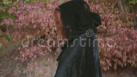 神秘的红发白种人女孩穿着黑色长袍转向相机提出红色苹果童话般的仙女视频的预览图
