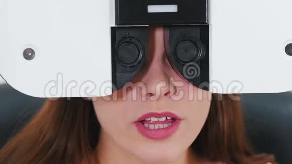 眼科治疗一名年轻妇女用特殊的验光设备检查视力一边说话视频的预览图