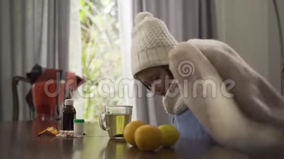 可爱的小白种人女孩戴着温暖的白色帽子和围巾用毯子盖住自己坐在桌子旁的孩子视频的预览图