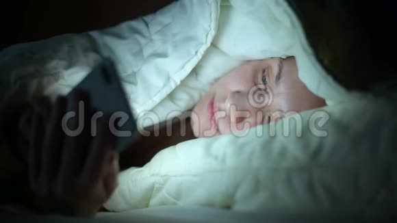 女孩晚上躺在被窝里用电话视频的预览图