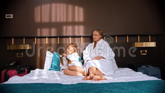 一家人在酒店房间里穿着白色浴袍爸爸把茶杯带到床上给他的妻子和女儿视频的预览图