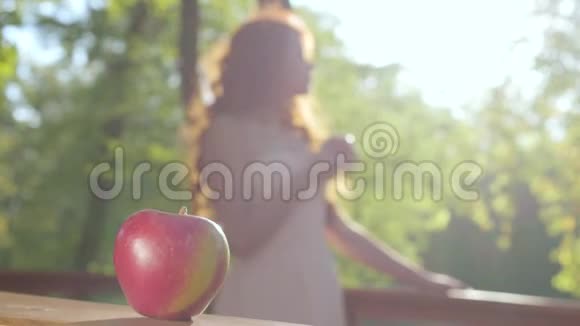 特写一个红苹果和一个红发白种人女人在阳光下的背景白雪公主风格童话森林视频的预览图