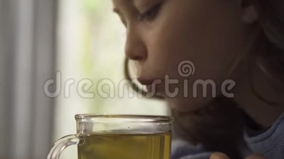 小女孩的特写脸吹在凉茶上然后一边喝一边坐在家里的桌子上孩子视频的预览图