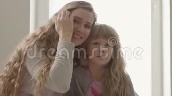 微笑的年轻女子看着相机拥抱着困倦的小女孩卡西亚妈妈和可爱的孩子在一起视频的预览图