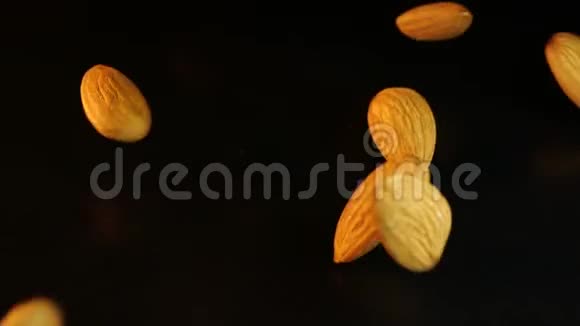 在黑色背景下拍摄碎杏仁开胃的特写镜头飞来的杏仁落在黑桌上视频的预览图