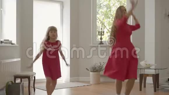 金发白种人的母亲和女儿在周末嬉戏穿着同样的红色裙子的漂亮女人和开朗的女孩视频的预览图