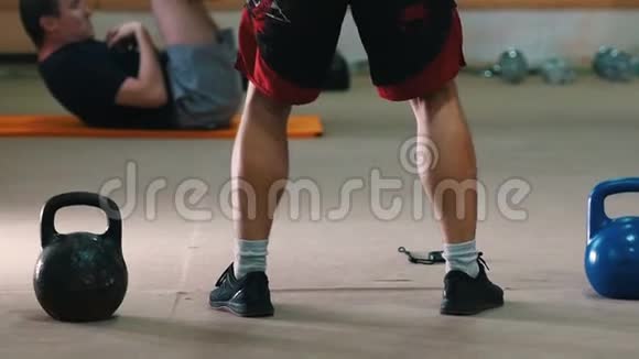 运动训练一个穿红色短裤的运动员双手抱着体重蹲着视频的预览图