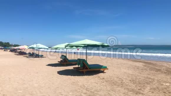 宽沙滩有许多日光浴床和雨伞Seminyak和Legian海滩在巴厘岛印度尼西亚4k录像视频的预览图