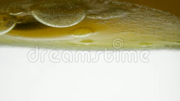 用茶匙搅拌的金色液体的特写镜头液体黄波线倒入香油和金黄色的近景视频的预览图