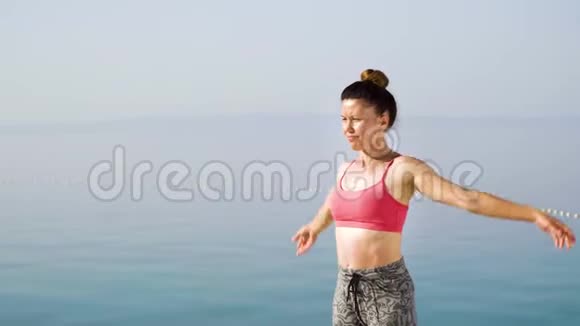 快乐的运动女子在海上码头练习瑜伽视频的预览图
