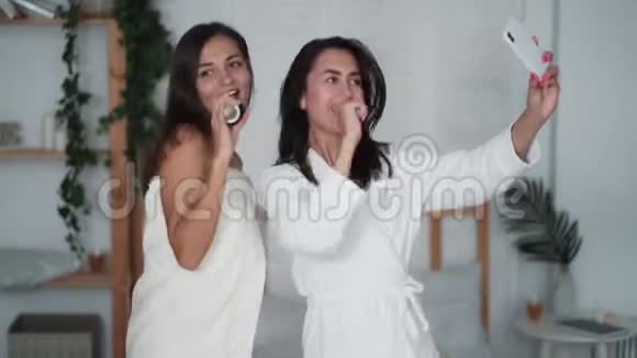 两个女孩穿着白色浴袍跳舞唱歌笑打电话自拍搞笑视频视频的预览图