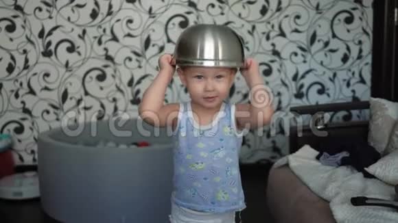 迷人的婴儿把一个大碗放在他的头上并在镜头前摆姿势视频的预览图