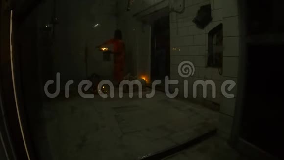 透过玻璃门印度教僧人在庙里散步盘子里放着蜡烛视频的预览图