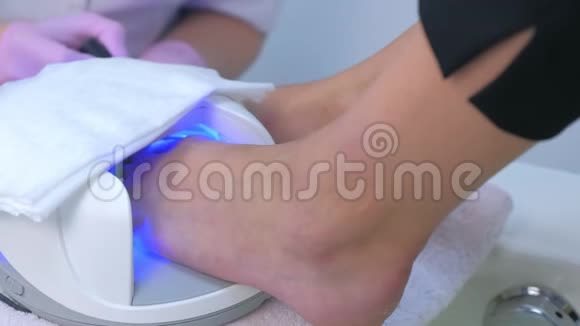 女人在美容院用紫外线灯晒虫胶脚趾特写镜头视频的预览图