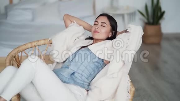 年轻漂亮的女人坐在扶手椅上微笑着梦想着休息着视频的预览图