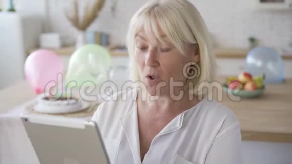 积极的成熟女人从平板电脑中得到令人惊讶的消息站在现代厨房里微笑生日视频的预览图