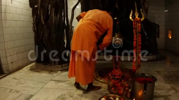 僧人穿着橘色的衣服在希夫林加附近挥舞扇子用鲜花装饰印度教晚会在希瓦寺内举行仪式视频的预览图
