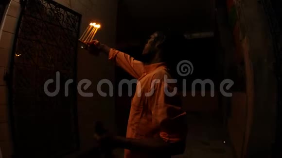 年轻的印度僧人在寺庙的夜晚甚至在黑暗中用燃烧的灯光重复动作视频的预览图