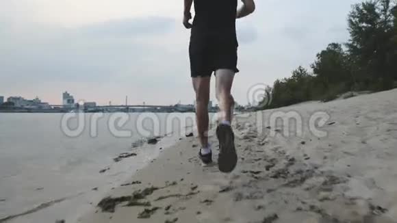 肌肉发达的雄腿沿着河滩奔跑晚上在河边慢跑的男腿附近有教养的男孩训练视频的预览图