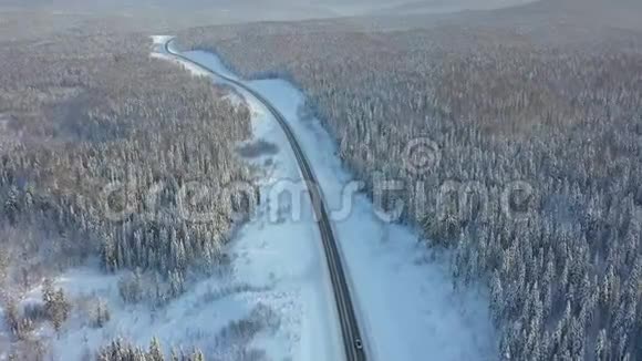 公路穿越冬林航拍无人机在高速公路上行驶汽车树上的雪视频的预览图