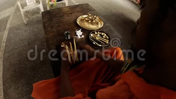 穿着橙色衣服的印度僧人把大棉衣系在灯具上视频的预览图