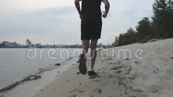 肌肉发达的雄腿沿着河滩奔跑傍晚在河边慢跑时可以欣赏苗条的男性腿年轻健康男视频的预览图