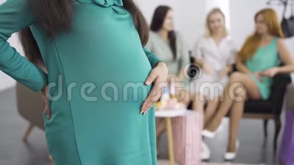穿蓝绿色连衣裙的孕妇腹部特写期待与她的三个朋友站在一起聊天视频的预览图