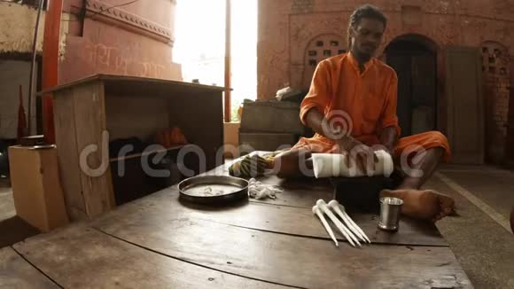 穿着橙色衣服的年轻印度僧人用棉花做蜱虫夜礼视频的预览图