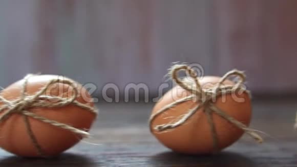 在模糊的木质背景下用细绳装饰的鸡棕色复活节彩蛋的特写镜头视频的预览图