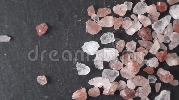 美丽的宏观镜头接近喜马拉雅山的盐躺在一块黑色的石头上各种品种的水晶粉红色白色视频的预览图