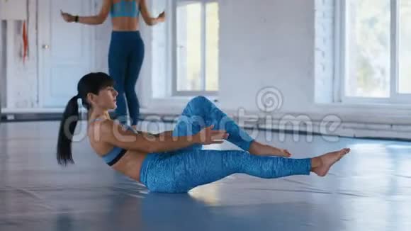 运动的女人在肮脏的健身房锻炼腹肌女运动员正在做V型仰卧起坐来改善肌肉视频的预览图